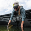 Woman wearing Lund Big Catch Hat while holding a fish in a Lund boat