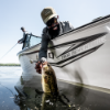 Man wearing Lund Channel Hat pulling up fish in Lund 1800 Adventure boat