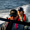 Man steering boat wearing Lund Camo Hat