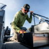 Man digging in boat's drawer wearing Lund Camo Hat